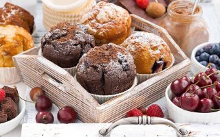 Horizontal image of a tray full of baked goods next to fresh fruit.