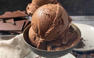 Horizontal image of a small metal goblet filled with scoops of dark brown ice cream.