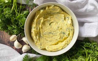 Horizontal top-down image of a white bowl filled with a creamy yellow mixture with green speckles on a white towel.