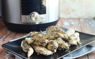 Horizontal image of seasoned white meat pieces on a black plate, with a kitchen appliance in the background.